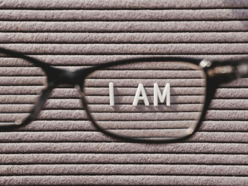 Top view on letter board with words I AM through eyeglasses. psychological self-regulation